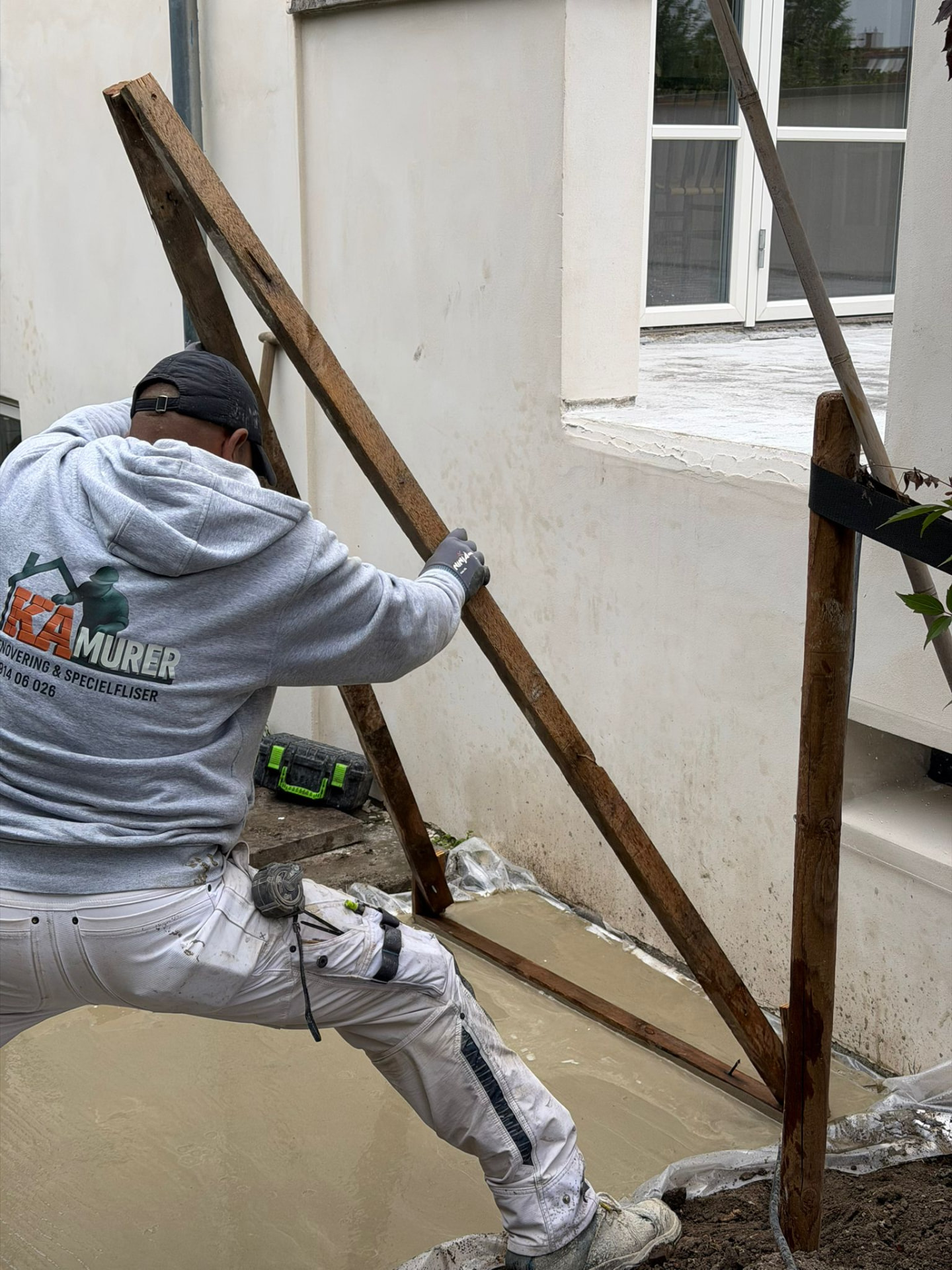 Murer fra KA MURER arbejder med forskalling ved nystøbt beton langs facade