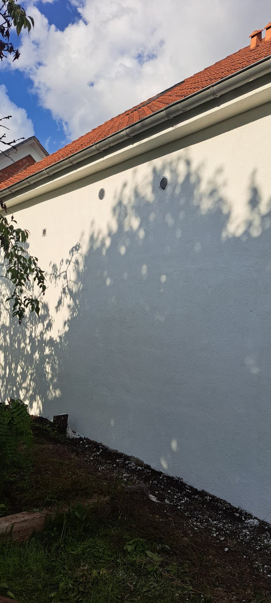 Facaden efter renovering med ensartet pudset og hvidmalet overflade