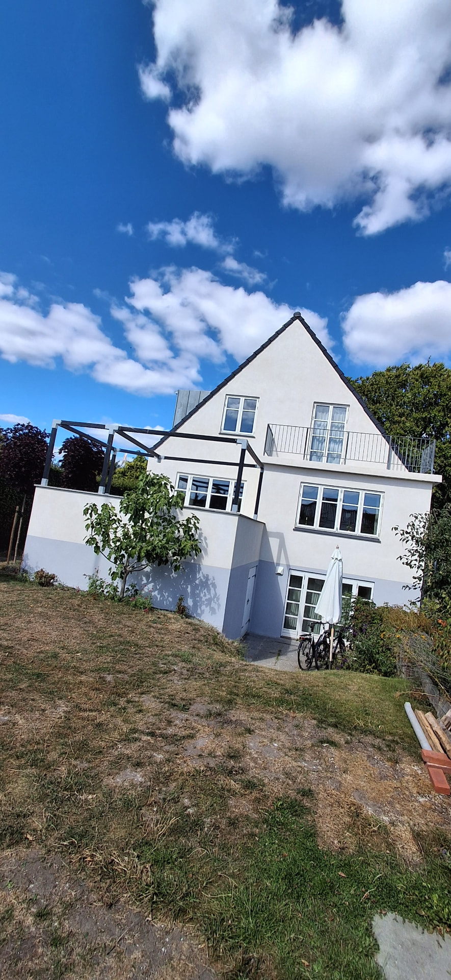 Villa med nypudset lys facade, gråblå sokkel og altan